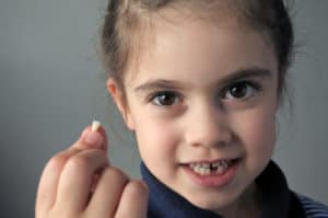 child holding her lost tooth