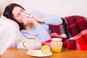 woman in bed with a cold with orange juice to drink