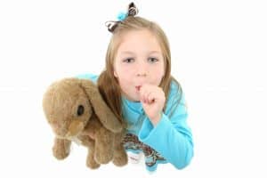 young girl holding her stuffed animal and sucking her thumb on white background
