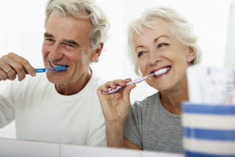 Senior Couple In Bathroom Brushing Teeth for Oral Health Senior Couple In Bathroom Brushing Teeth for Oral Health