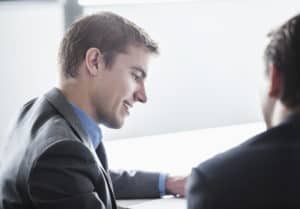 Two business people smiling and looking down at a business meeting