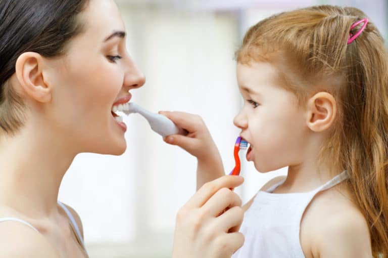mother and daughter brushing each other's teeth