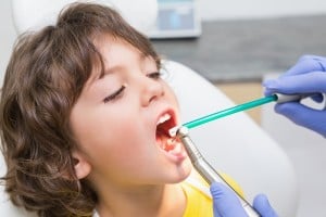 Kid's dentist examines boy's teeth for sealant needs