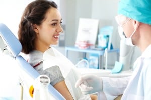 Young female patient looking at dentist while he describing the