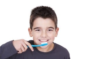young boy brushing his teeth before school and smiling