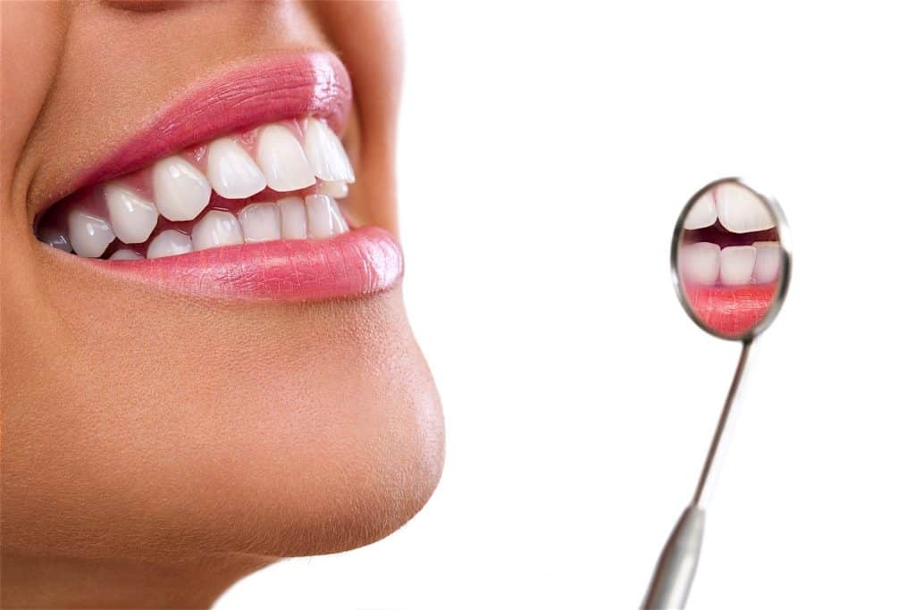 Healthy woman teeth and a dentist mouth mirror