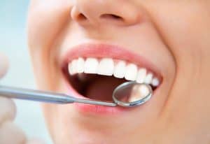 dentist checking woman's loose tooth