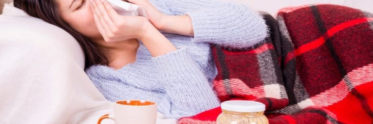 woman in bed with a cold with orange juice to drink