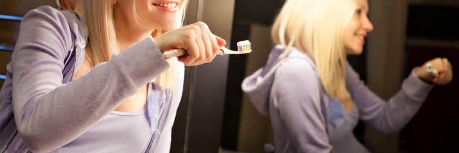 Pregnant woman cleaning her teeth at bathroom