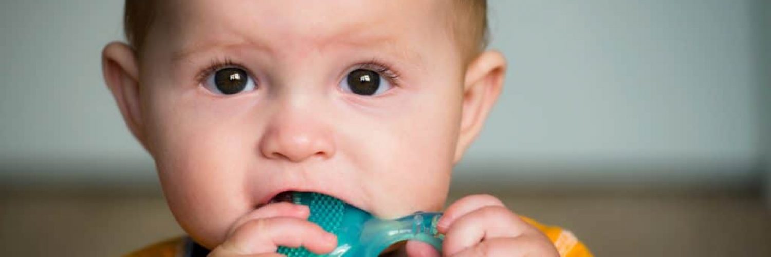 Baby chewing on teething ring toy