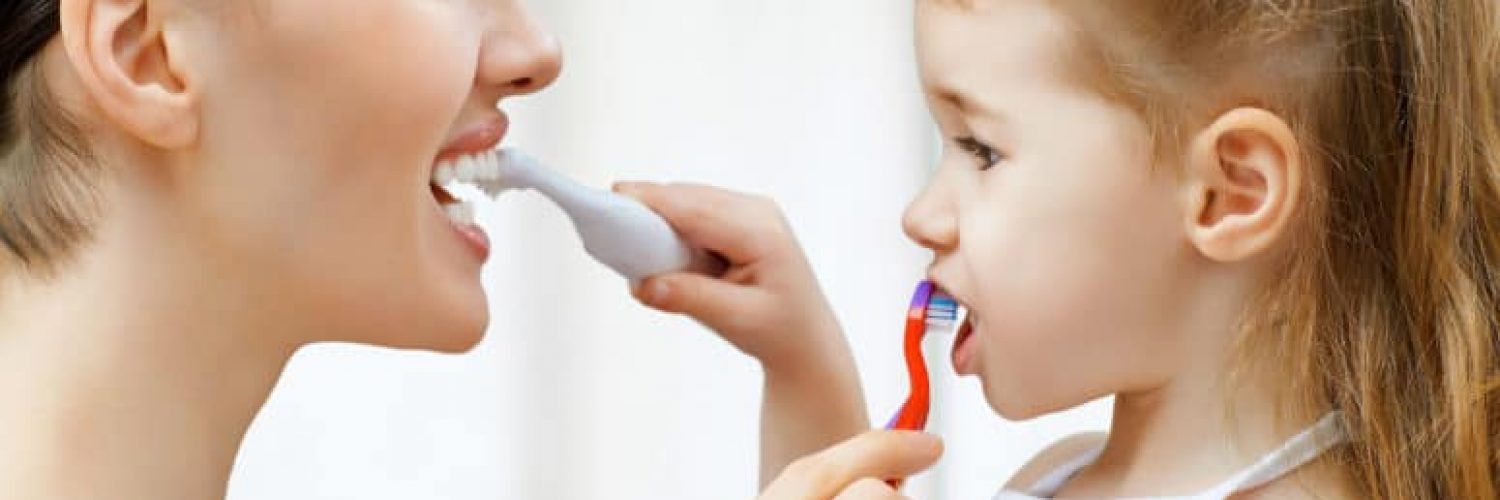 mother and daughter brushing each other's teeth