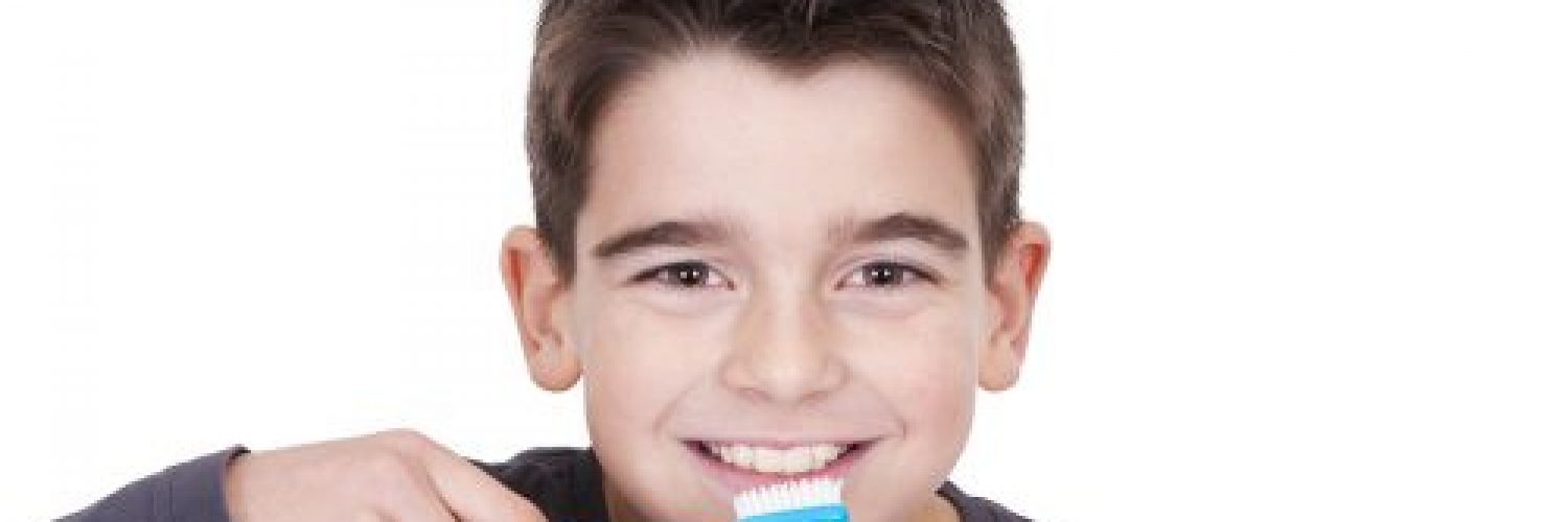 young boy brushing his teeth before school and smiling