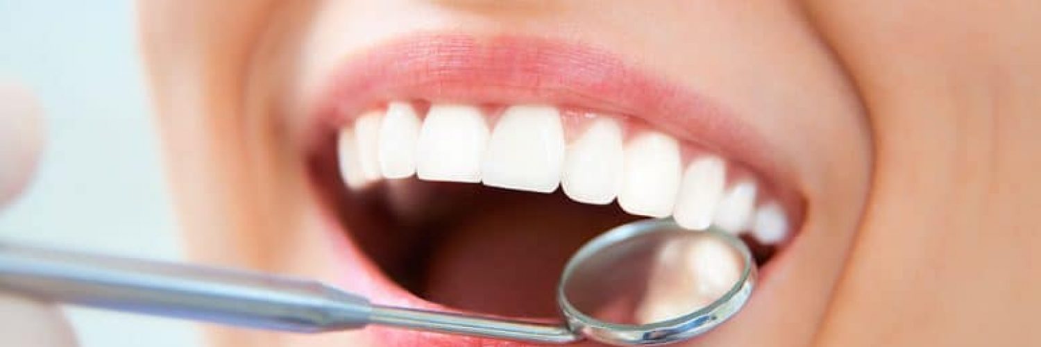 dentist checking woman's loose tooth