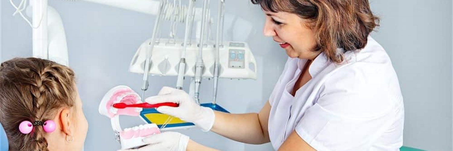 Dental Hygienist teaching child proper way to brush