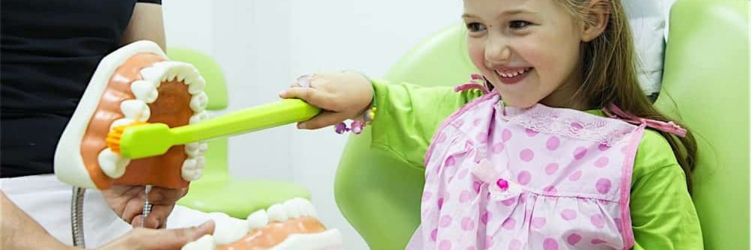 Dentist teaching child how to brush teeth