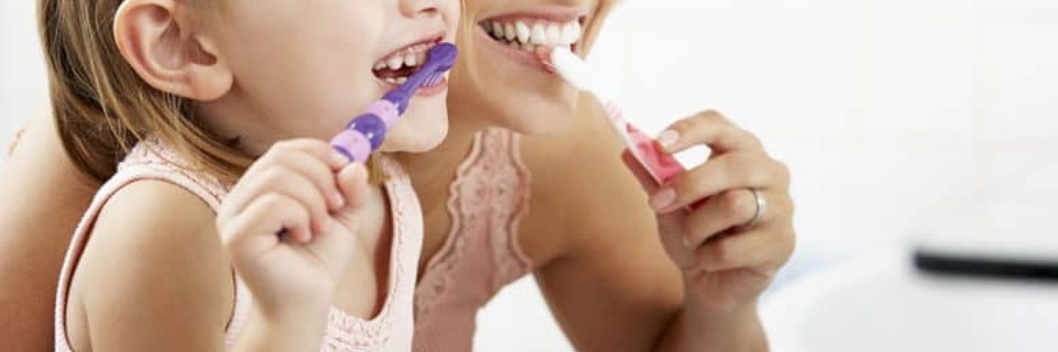 A mother and daughter brushing their teeth before the dentist