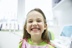 Girl showing her healthy milk teeth at dental office