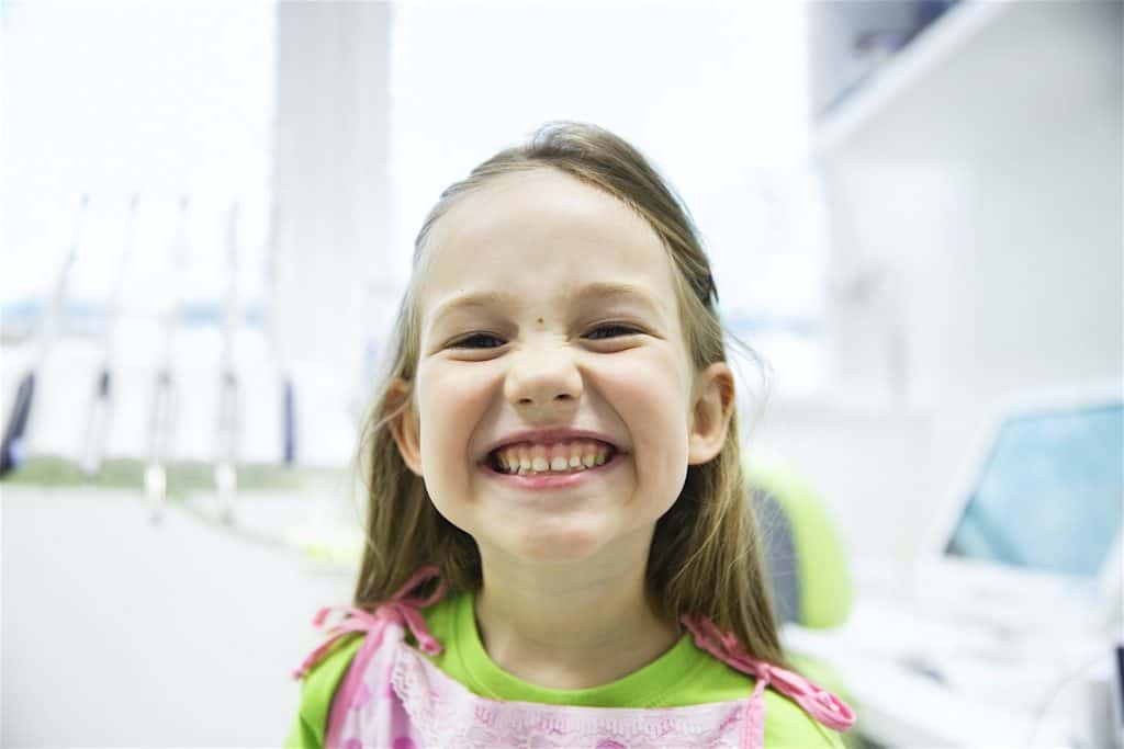 Girl showing her healthy milk teeth at dental office Girl showing her healthy milk teeth at dental office