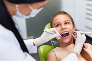 Teeth checkup at dentist's office. Dentist examining girls teeth in the dentists chair