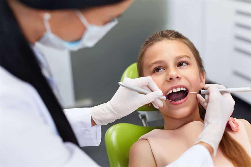 Teeth checkup at dentist’s office. Dentist examining girls teeth in the dentists chair Teeth checkup at dentist's office. Dentist examining girls teeth in the dentists chair