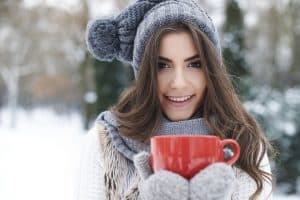 Woman drinking a hot drink in cold air.