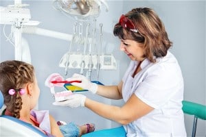 Dental Hygienist teaching child proper way to brush