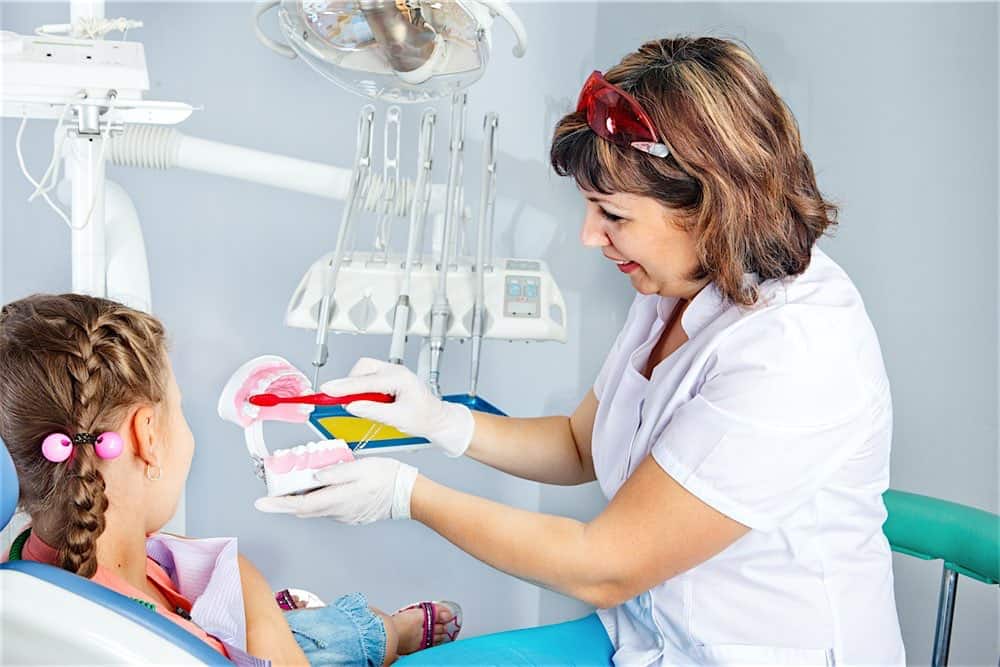 Dental Hygiene Dental Hygienist teaching child proper way to brush