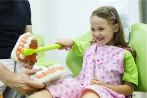 Dentist teaching child how to brush teeth