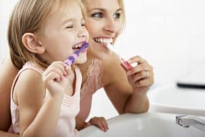 A mother and daughter brushing their teeth before the dentist